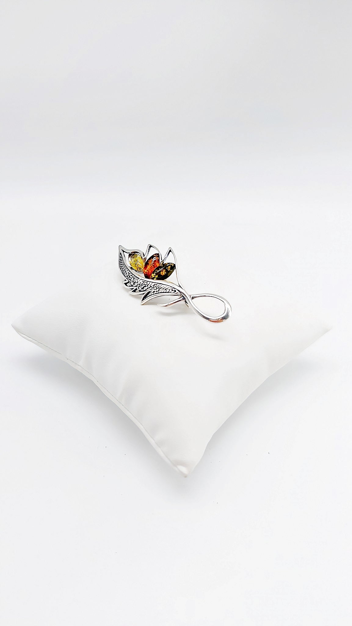 Filigree silver brooch with multicolored amber